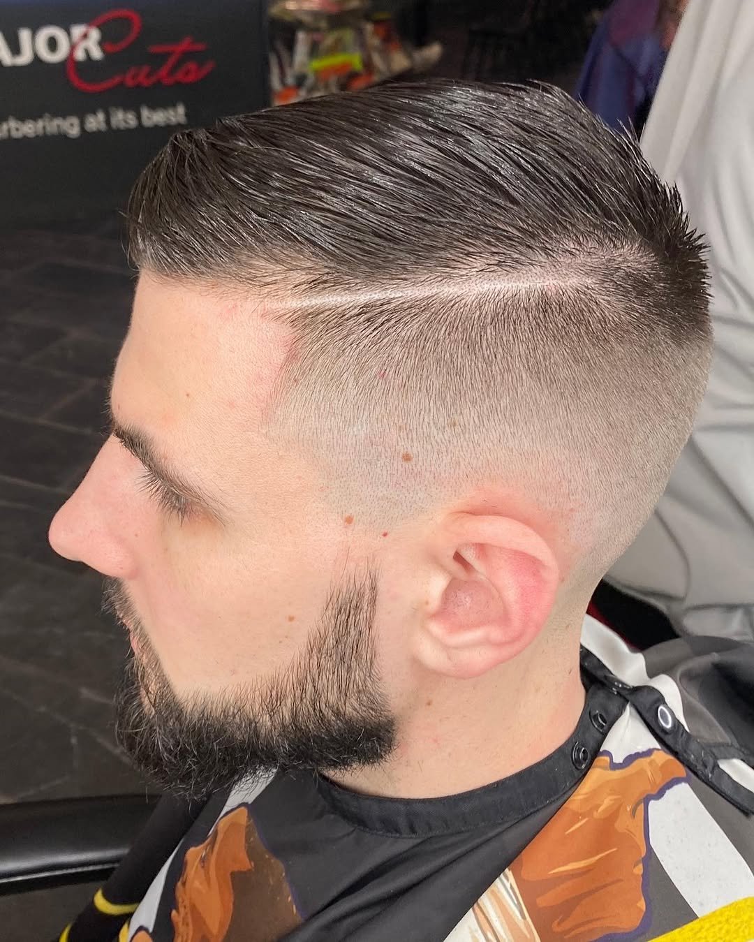 Comb-over with a hard part, taper fade and beard